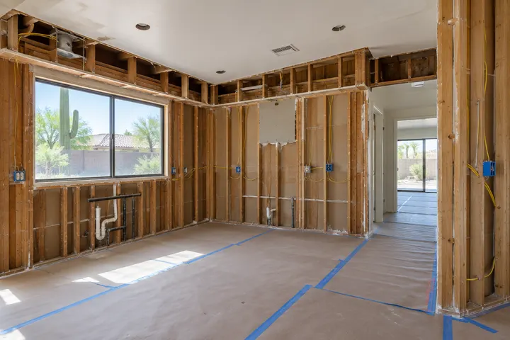 Kitchen during demolition with soffits removed, cabinets gone, studs and new wiring exposed and floors covered